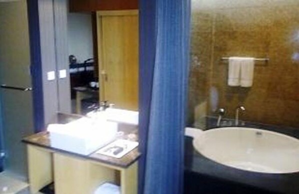 A bathroom with a sink, mirror, and bathtub.
