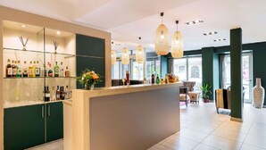 Un espace bar moderne avec un comptoir en bois, des étagères remplies de bouteilles et des lampes suspendues.
