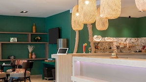 Un espace d’accueil moderne agrémenté d’un mur végétal, d’étagères en bois, d’un ordinateur portable et d’un coin salon avec des chaises et une petite table.