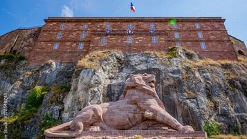 Un edificio de ladrillo grande con una estatua de león en primer plano.