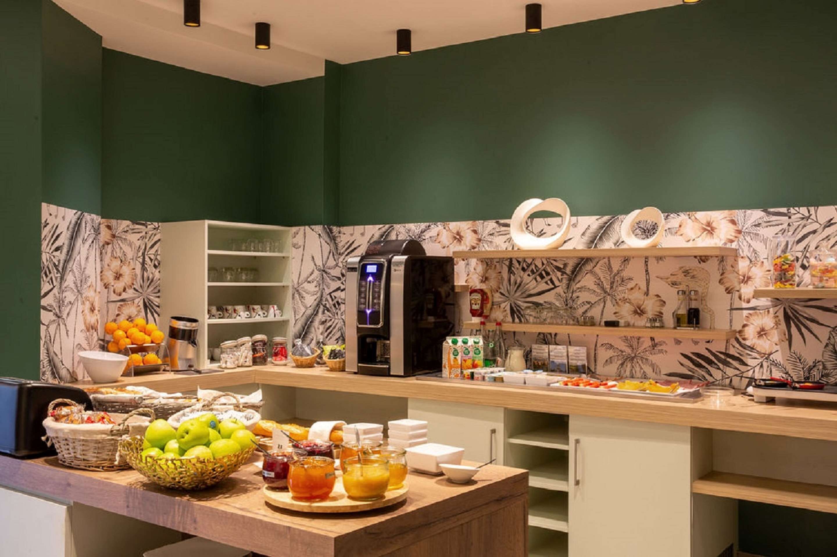 A buffet setup with various food items and beverages, a coffee machine, and a fruit bowl.
