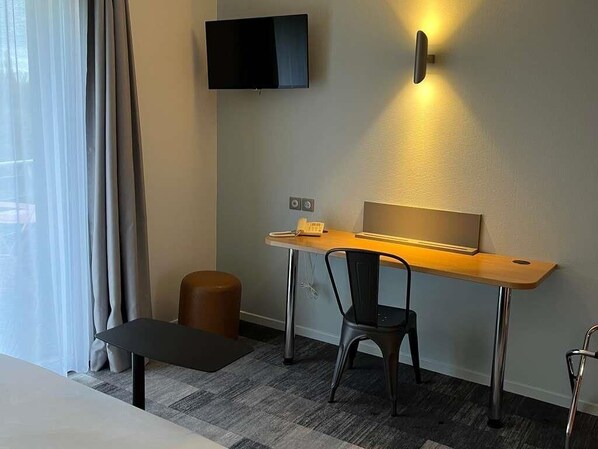 A hotel room with a desk, chair, TV, and a small stool. - ibis Styles Bourbon Lancy (Bourbon-Lancy)