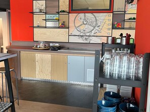 A modern kitchen with wooden cabinets, a built-in oven, and a red accent wall. - ibis Styles Bourbon Lancy (Bourbon-Lancy)