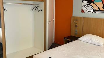 A bedroom with a bed, a wardrobe, and a small table.
