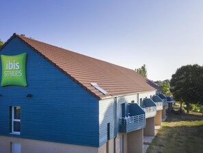 A building with a blue exterior and a green sign labeled "ibis Styles". - ibis Styles Bourbon Lancy (Bourbon-Lancy)
