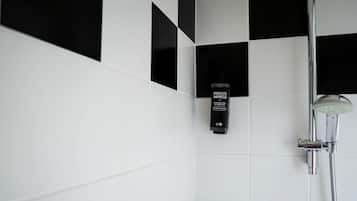A modern bathroom with a black and white checkered wall, a handheld showerhead, and a bottle of body lotion.
