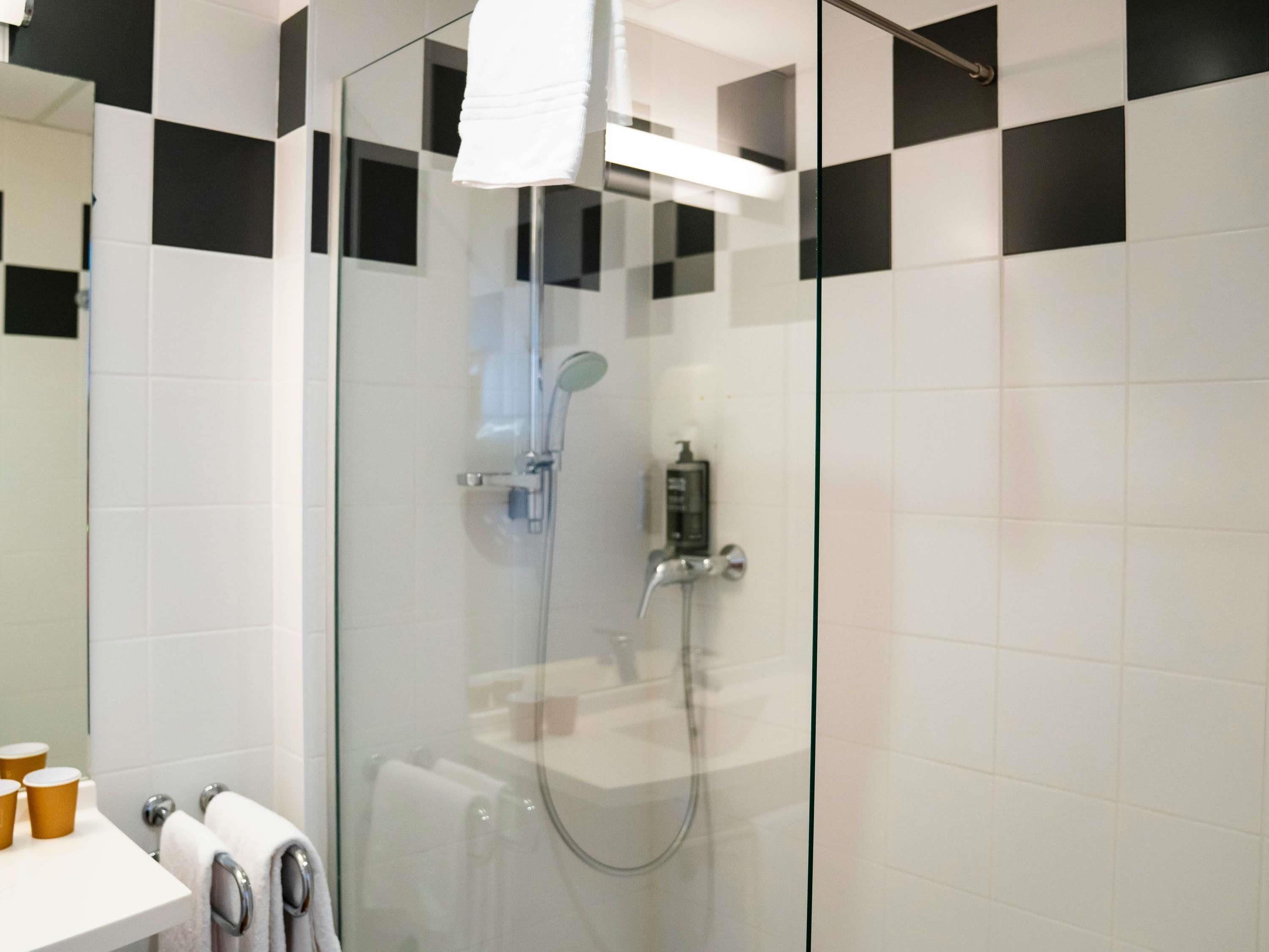 Un baño moderno con ducha de vidrio, azulejos blancos y un perchero para toallas.