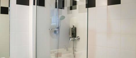 A modern bathroom with a glass-enclosed shower, white tiles, and a towel rack.