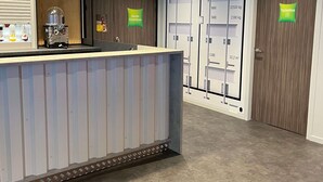 A reception area with a counter, a coffee machine, and a wall-mounted display. There are doors labeled with weight and volume limits. - ibis Styles Bourbon Lancy (Bourbon-Lancy)