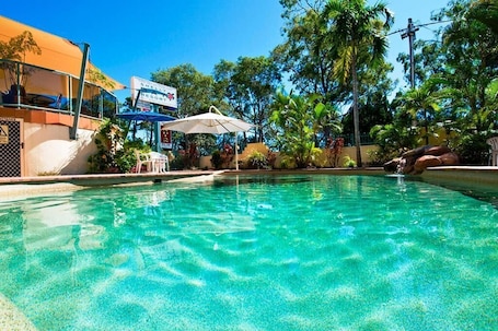 Una piscina al aire libre, sombrillas, sillones reclinables de piscina