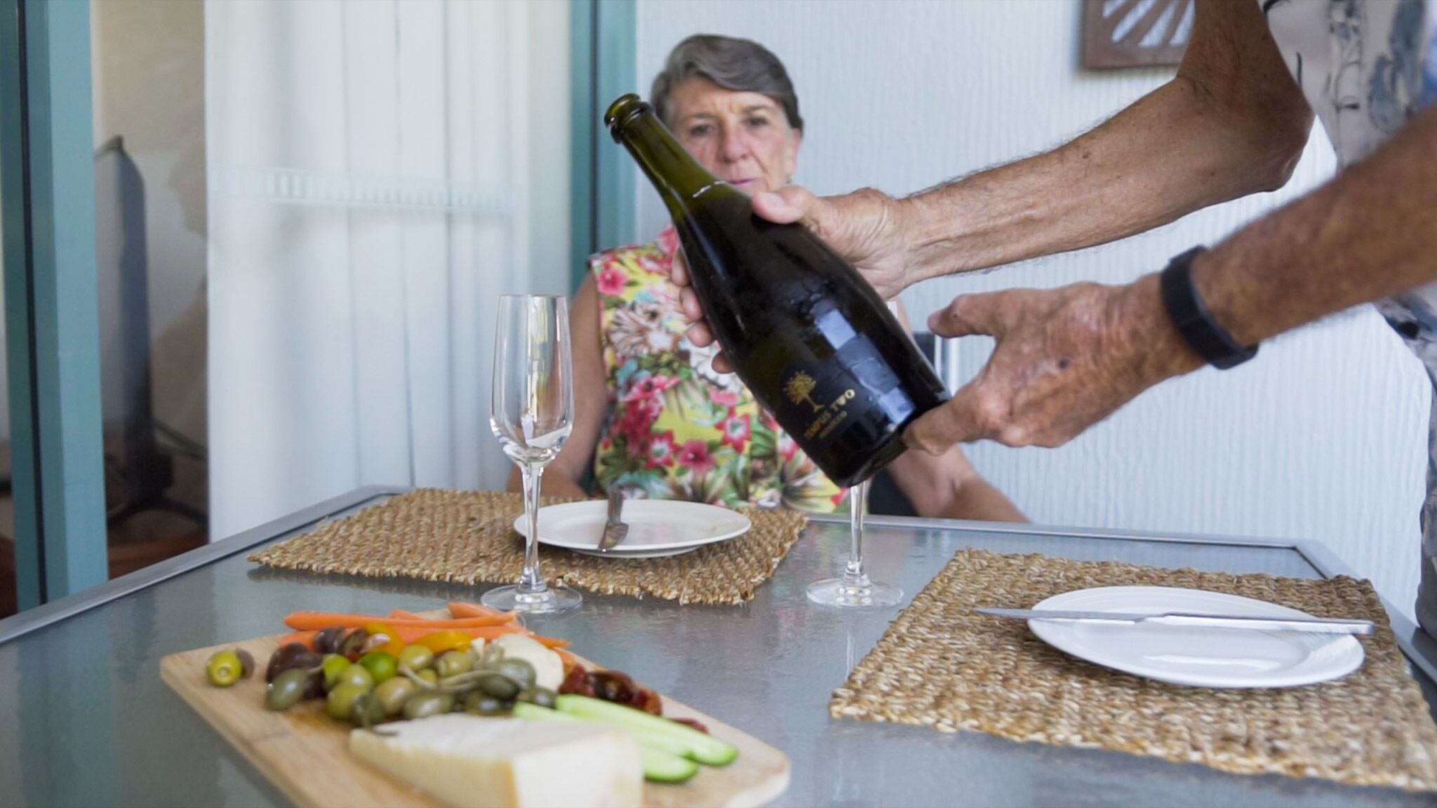 Une table avec une bouteille de vin, un verre et une assiette de nourriture.