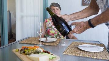 Une table avec une bouteille de vin, un verre et une assiette de nourriture.