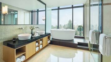 A modern bathroom with a large bathtub, a double sink vanity, and a large mirror.