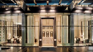 A modern hotel lobby with a glass entrance, a central chandelier, and a carpeted area. - The St. Regis Bangkok (Bangkok)