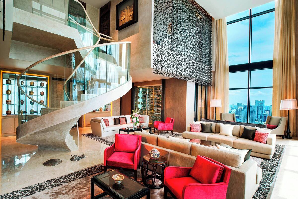 A spacious lobby with a modern staircase, comfortable seating areas, and large windows offering a city view.