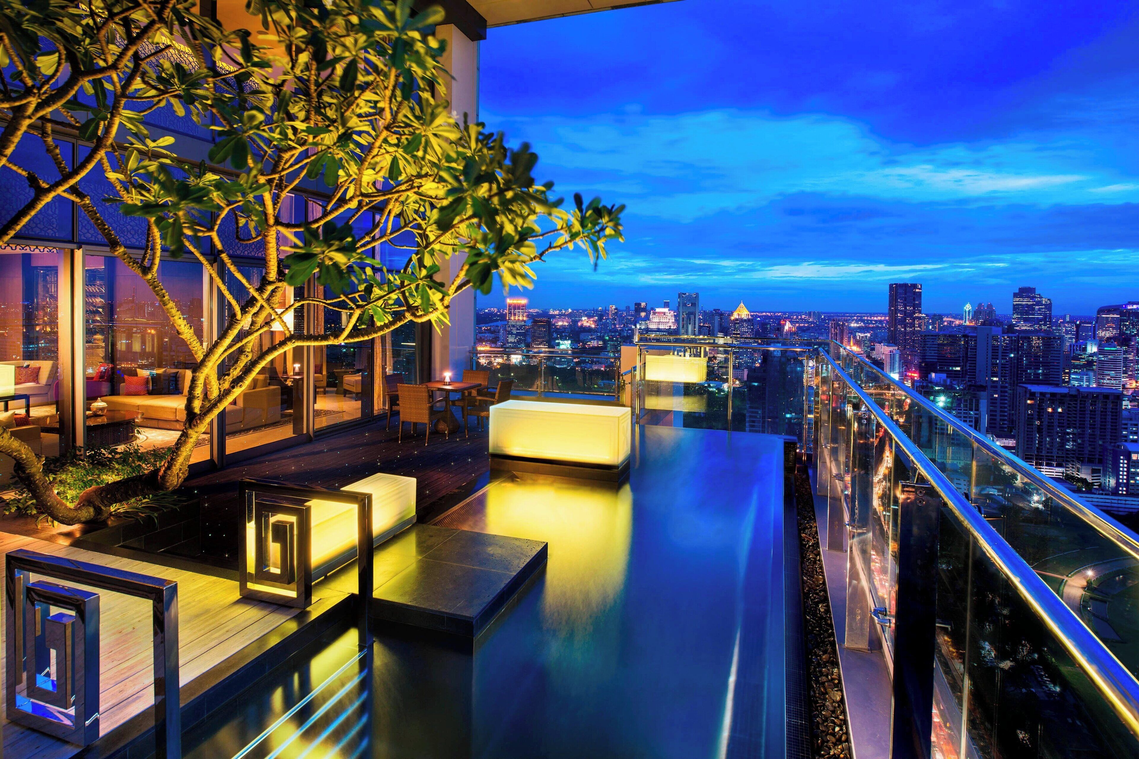 A rooftop terrace with a city view, seating areas, and a glass railing.