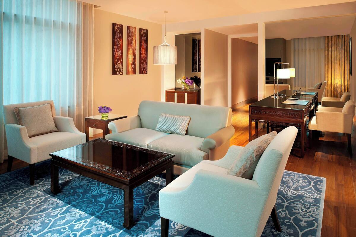 A modern living room with a sofa, armchairs, a coffee table, and a dining area.