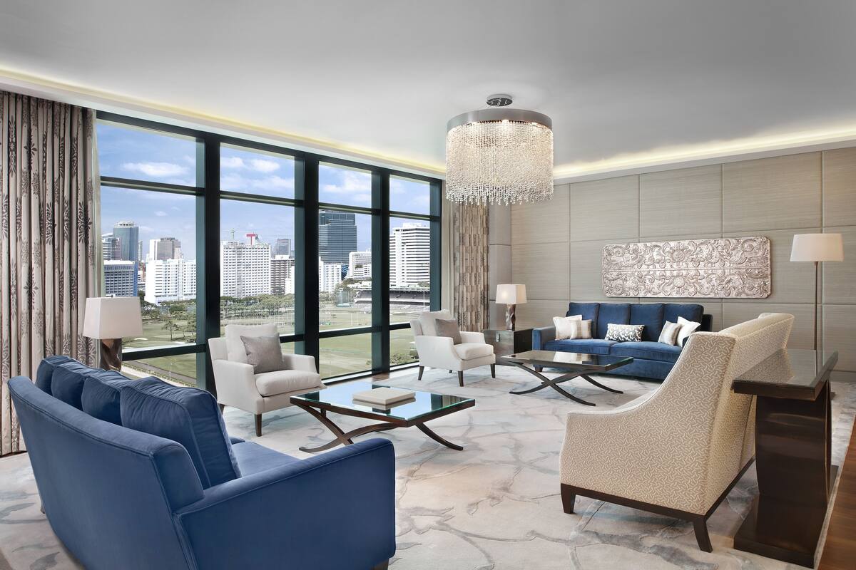 A modern living room with a large window, a chandelier, and a city view.