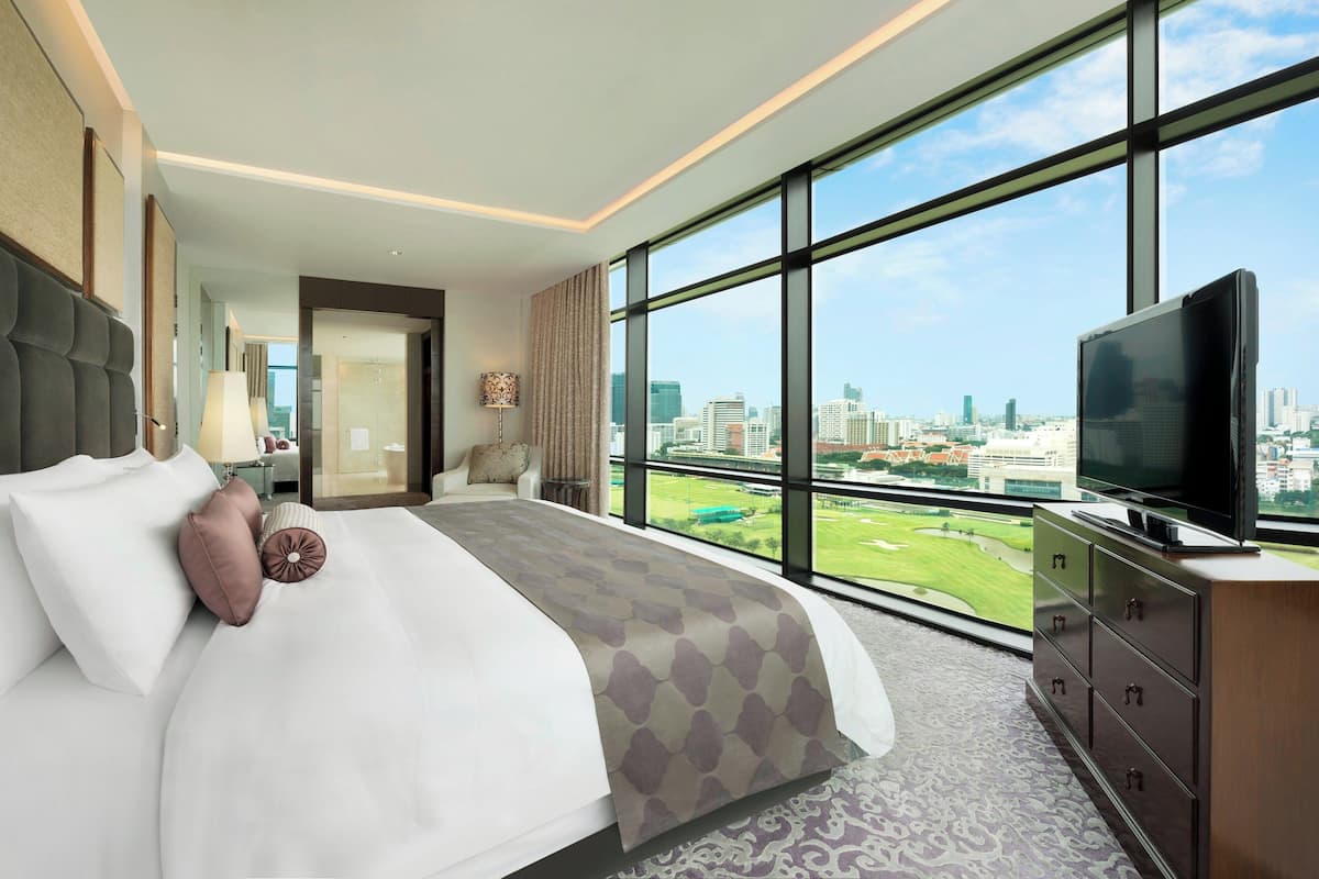 A modern hotel room with a large bed, a TV, and a city view.