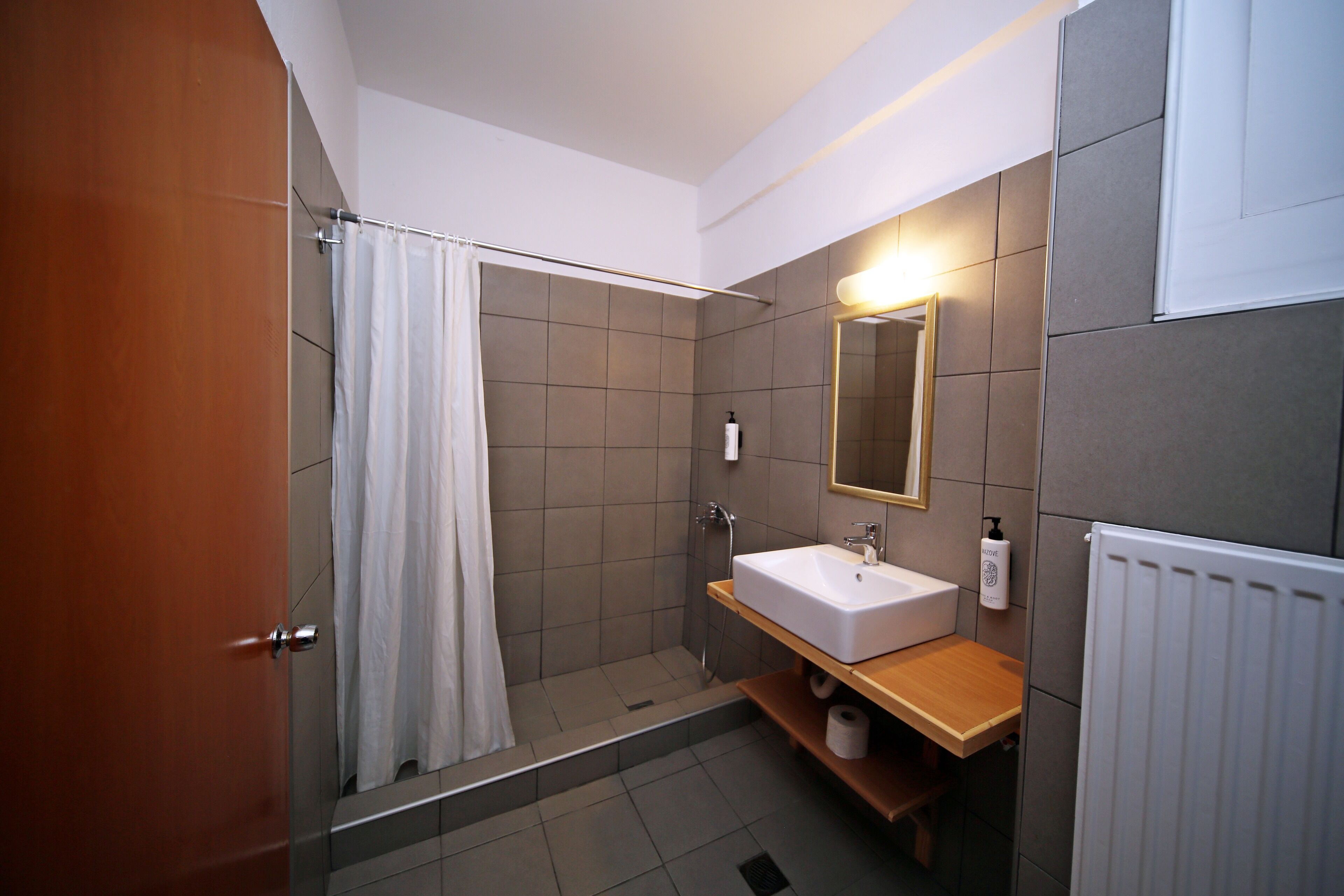 Un baño moderno con ducha, lavamanos y espejo.