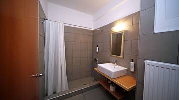 Un baño moderno con ducha, lavamanos y espejo.