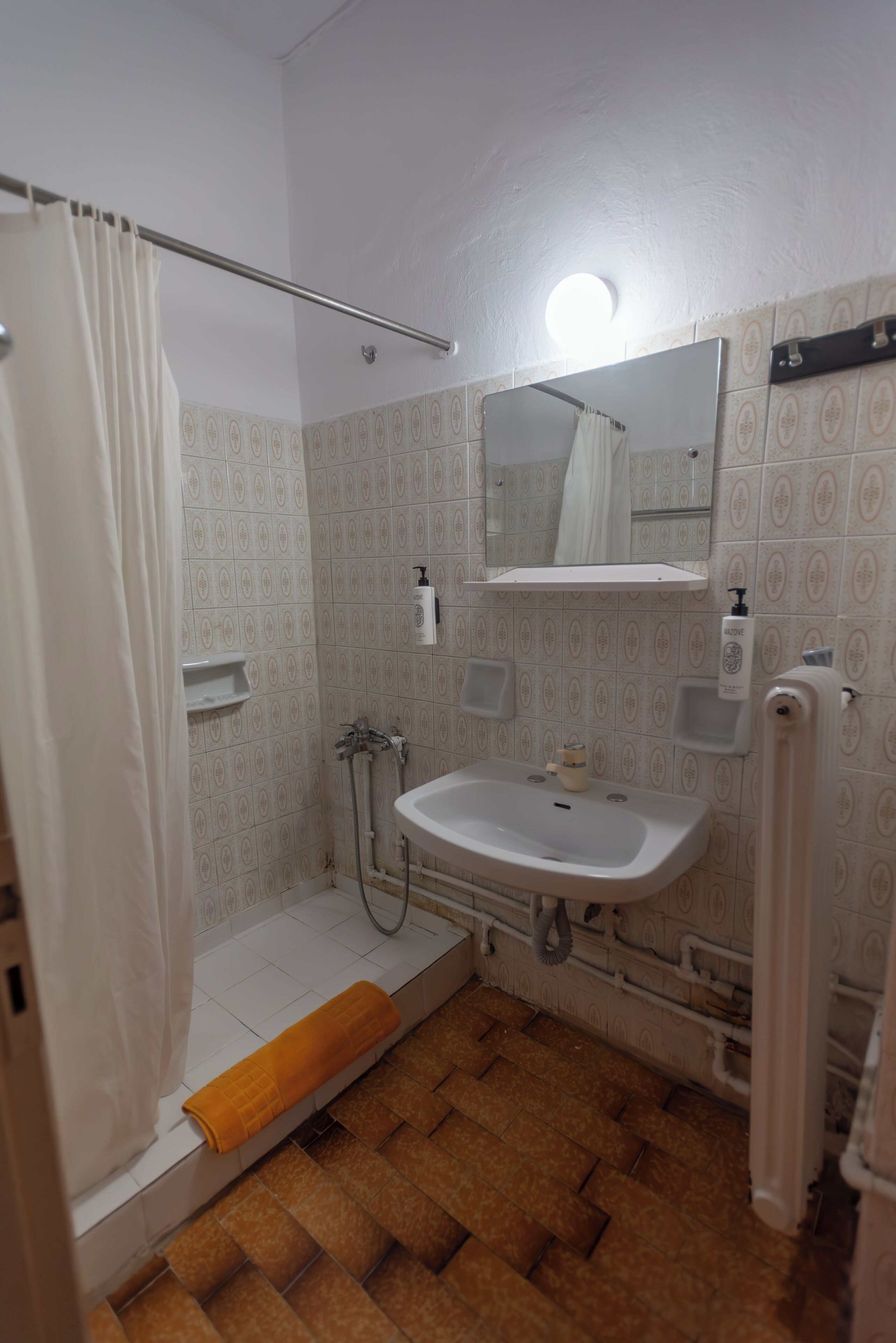 Casa de banho com chuveiro, lavatório e espelho.