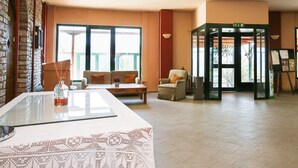 A lobby with a reception desk, seating area, and a revolving door. - Lecadin Hotel (Karpenisi)