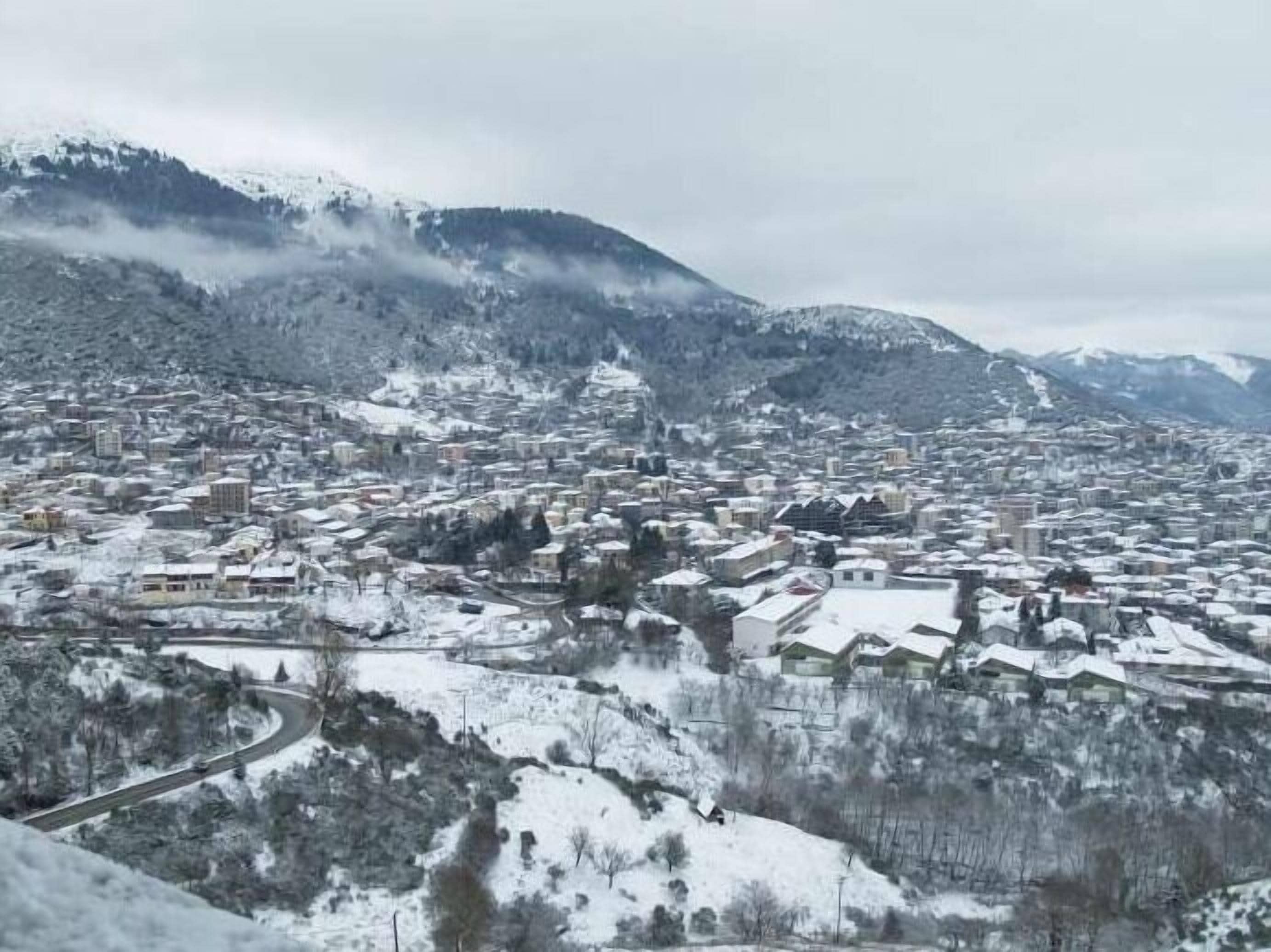 Un pueblo cubierto de nieve, con edificios y una carretera sinuosa.