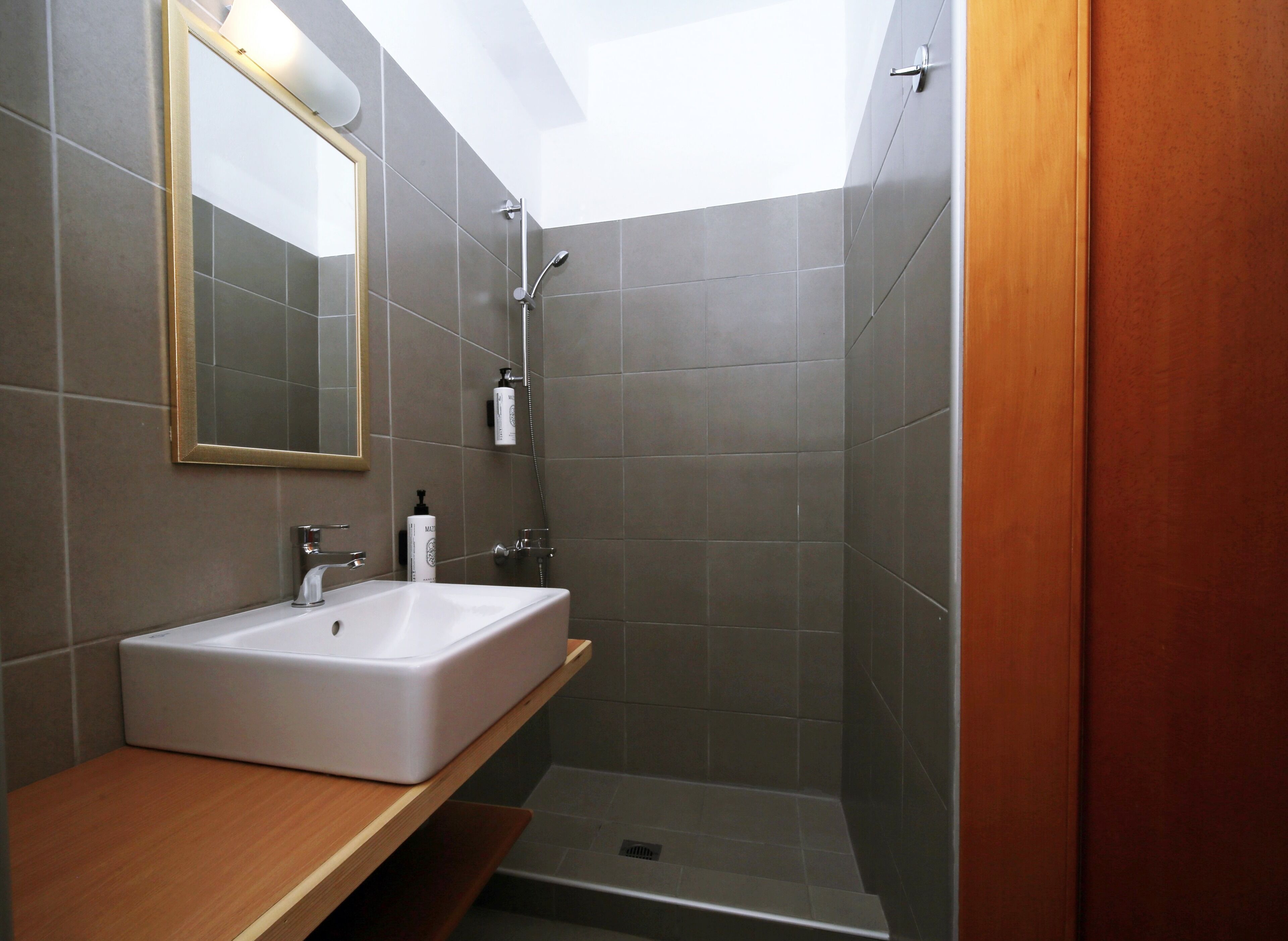 Une salle de bain moderne avec un lavabo blanc, un miroir et une douche.