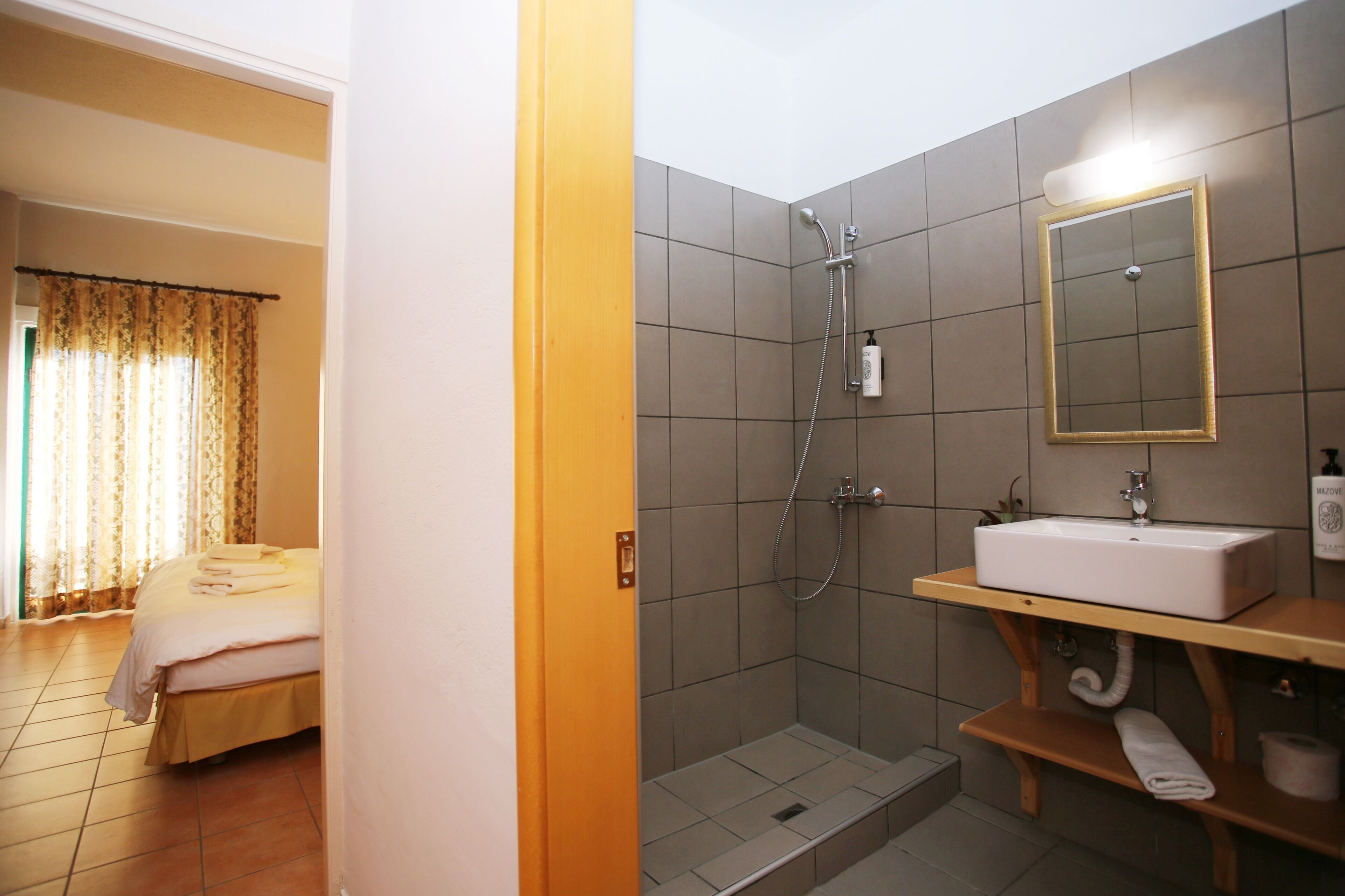 Een hotelkamer met een bed, douche en wastafel met spiegel.