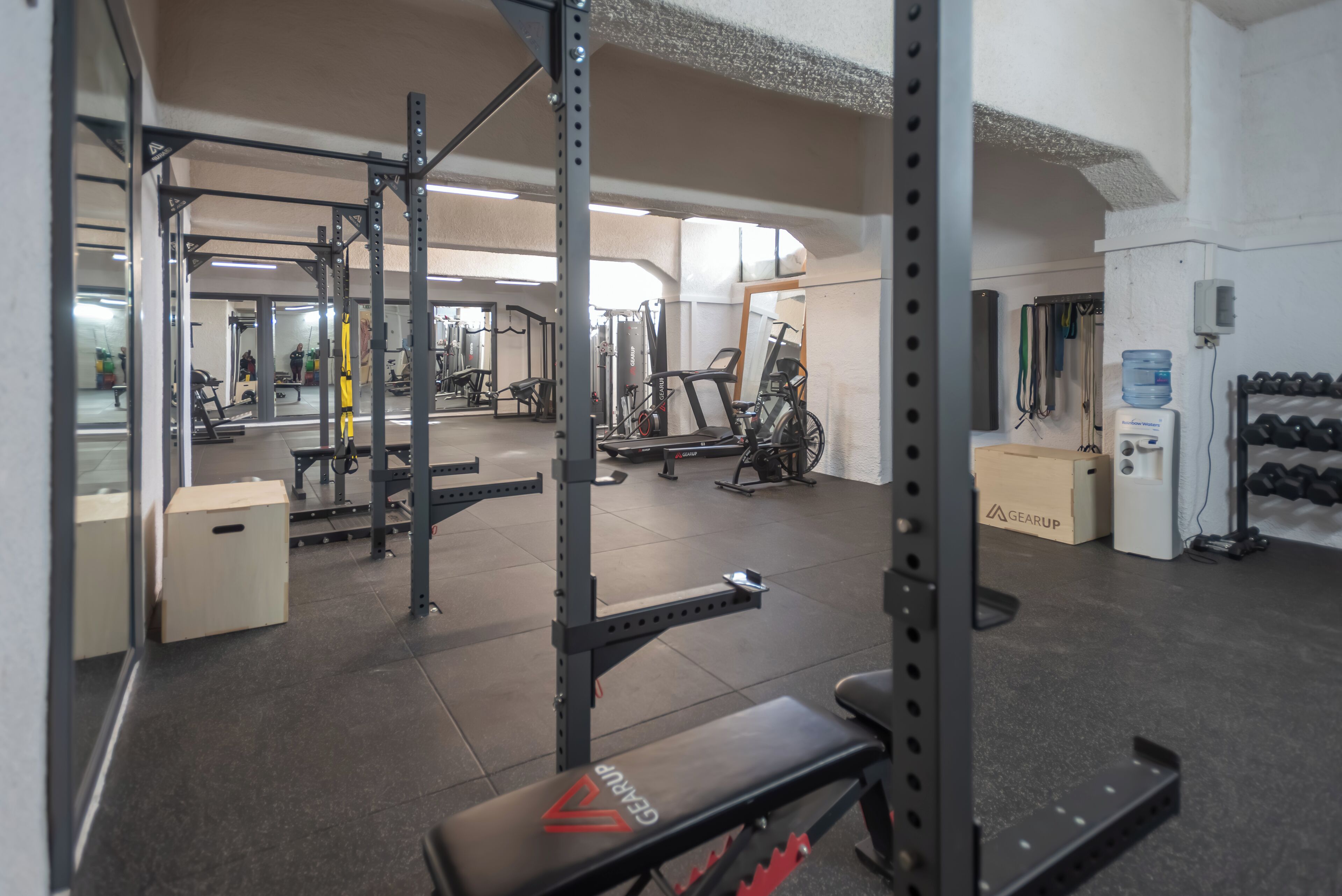 A gym with weightlifting equipment, cardio machines, and a mirror.