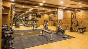 A gym with various exercise equipment, mirrors, and wooden walls. - The Ocean Pearl (Mangaluru)