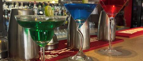 Tre bicchieri da martini su un bancone del bar, con un sottobicchiere rosso sottostante.