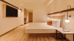 A modern hotel room with a large bed, bedside table, and a flat-screen TV mounted on the wall. - Red Fox by Lemon Tree Hotels, Hyderabad (Hyderabad)