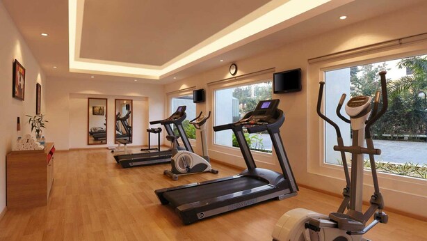 A fitness room with treadmills, an elliptical, and a stationary bike, with large windows and a clock on the wall. - Red Fox by Lemon Tree Hotels, Hyderabad (Hyderabad)
