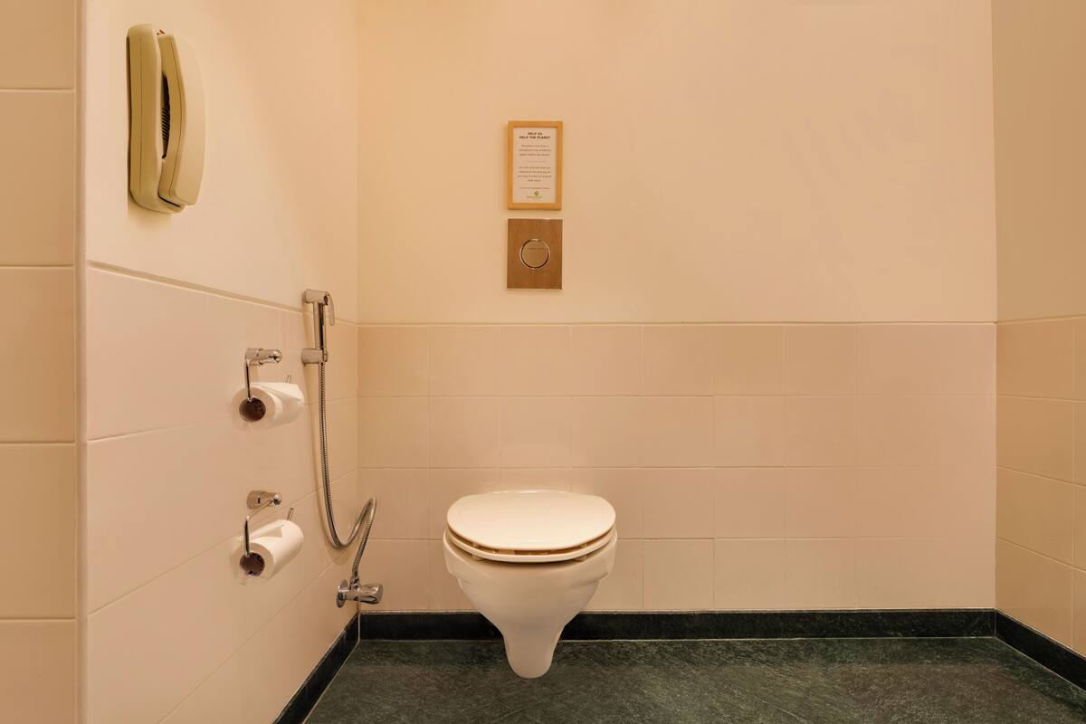 Un baño con inodoro, secador de manos y dispensador de toallas de papel.