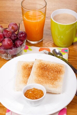 A breakfast setting with toast, a glass of orange juice, a mug, and a bowl of jam. - Quinta Río Boutique Hotel (Querétaro)