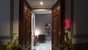 A hallway with wooden doors, a black chair, and a red lamp. - H Rooms Boutique Hotel (Naples)