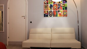 A modern room with a beige sofa, a colorful abstract painting, and a floor lamp. - H Rooms Boutique Hotel (Naples)