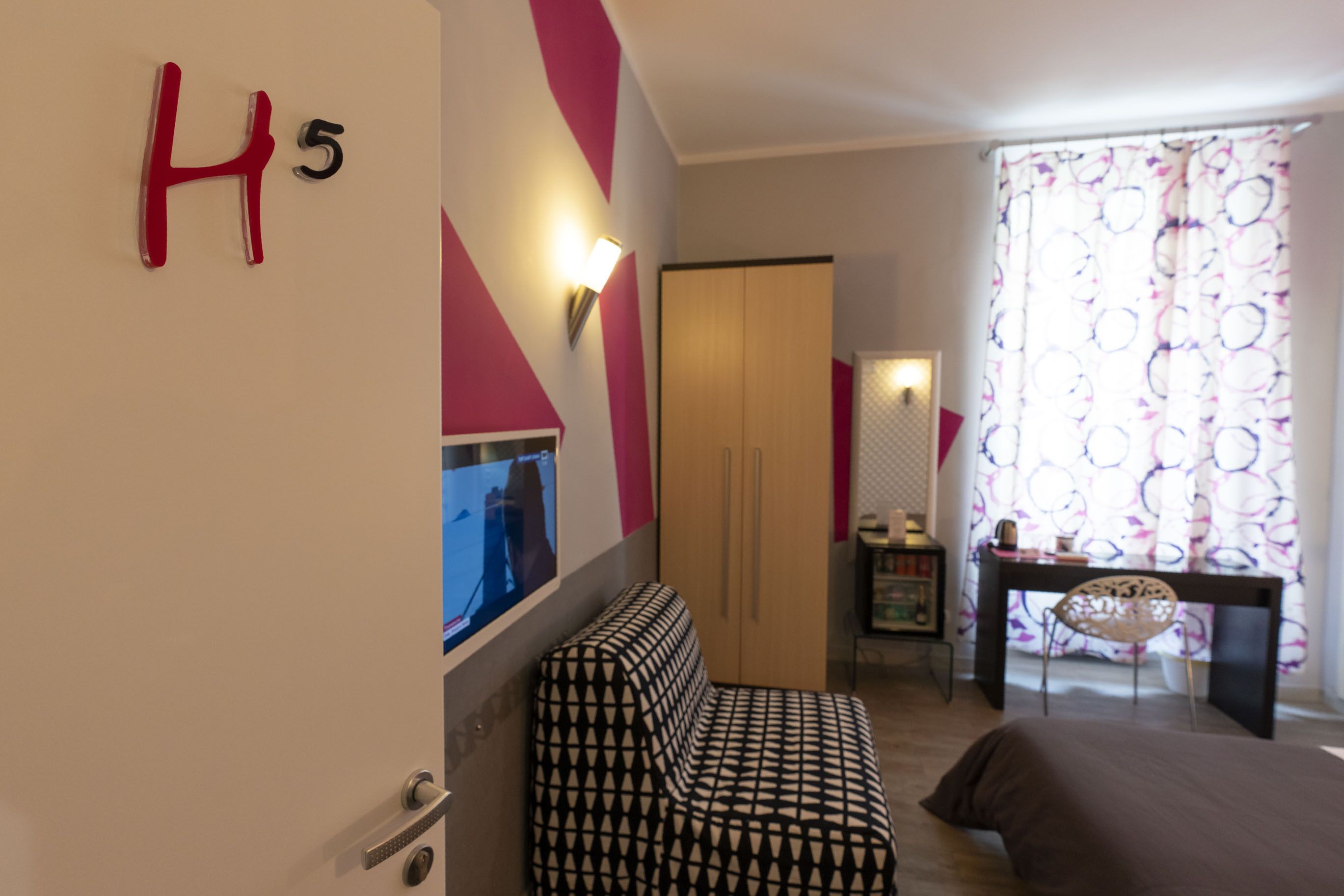 A hotel room with a bed, a sofa, a desk, and a wardrobe.
