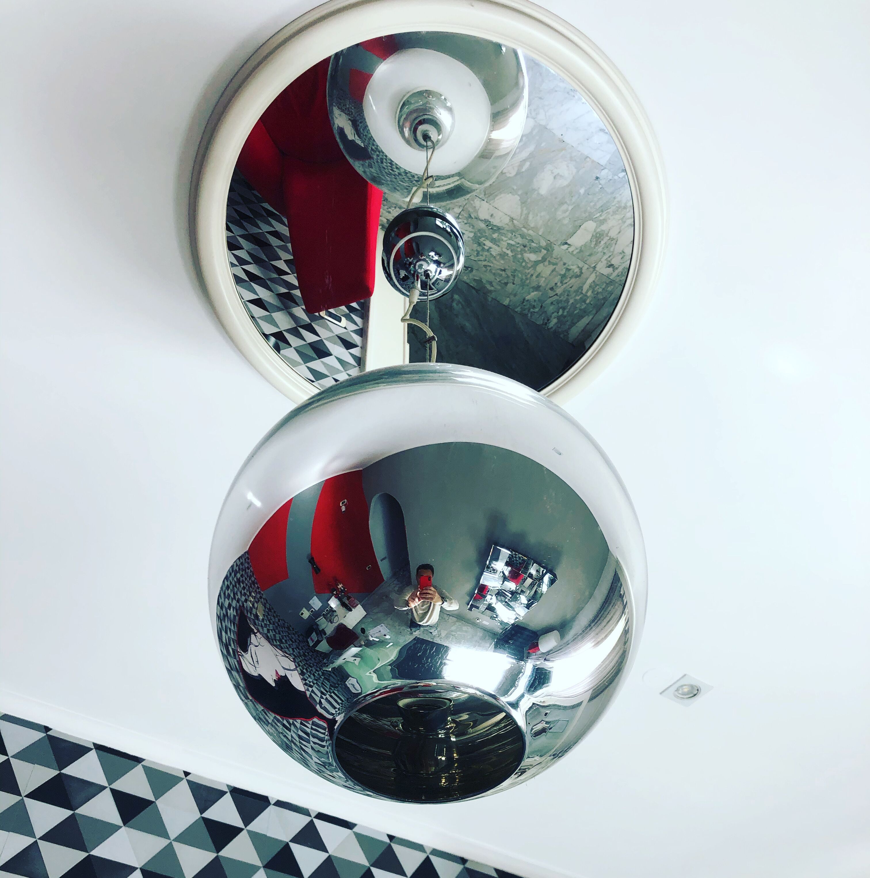 Two large, reflective spherical mirrors mounted on a white wall.
