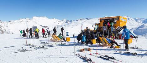 A ski resort with a snow food truck and a group of people preparing for skiing.