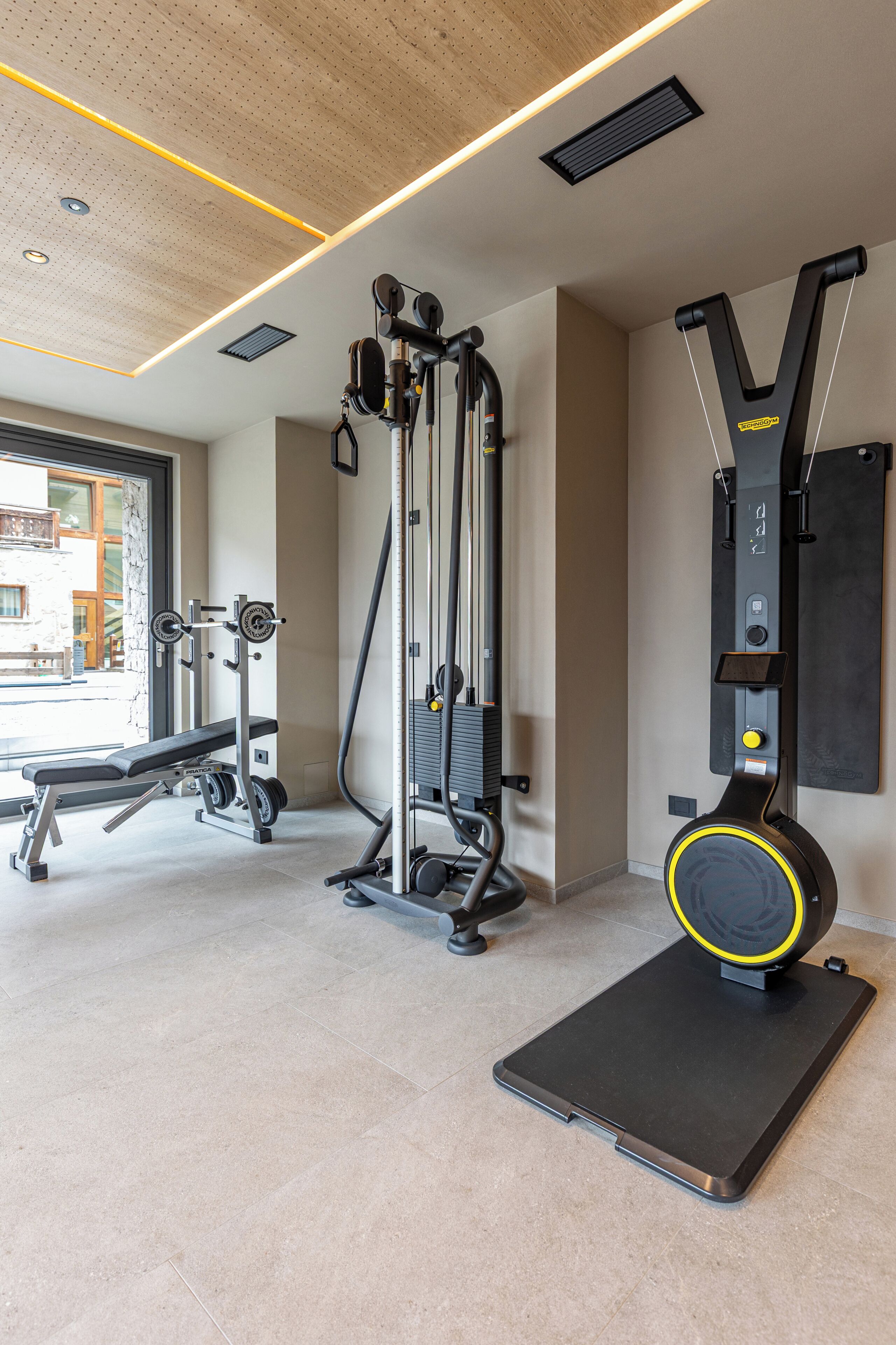 Ein Fitnessraum mit Trainingsgeräten, einer Bank und einem an der Wand befestigten Gerät.