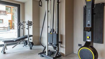 Ein Fitnessraum mit Trainingsgeräten, einer Bank und einem an der Wand befestigten Gerät.