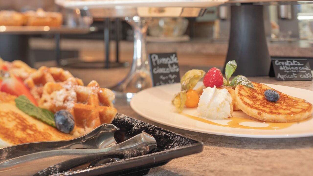 A breakfast buffet with waffles, pancakes, and various toppings.