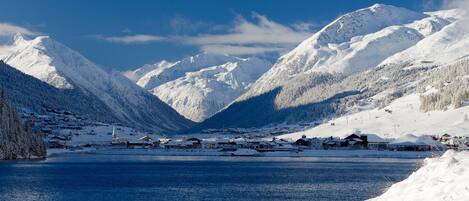 Un paysage montagneux enneigé avec un petit village au bord d’un lac.