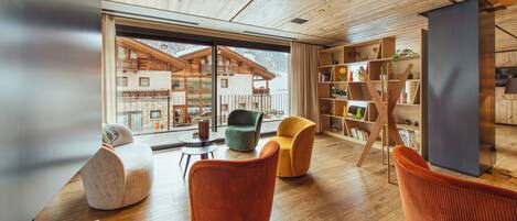 Um interior moderno com soalho de madeira, uma janela grande e uma estante de livros.