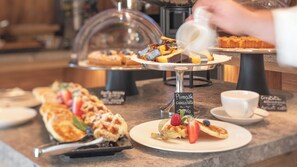 A breakfast buffet with various pastries and a sign indicating a plum cake.