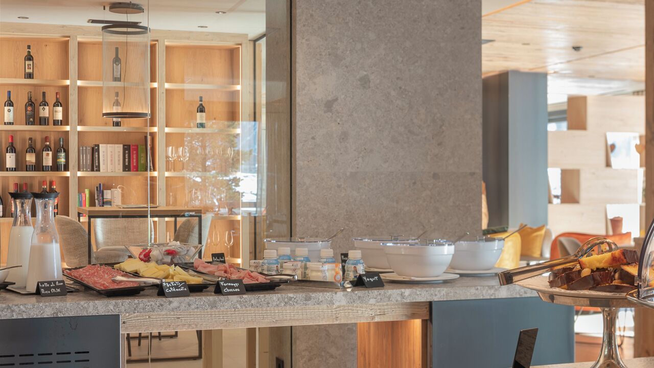A hotel breakfast area with a marble counter, wine bottles, and various food items.