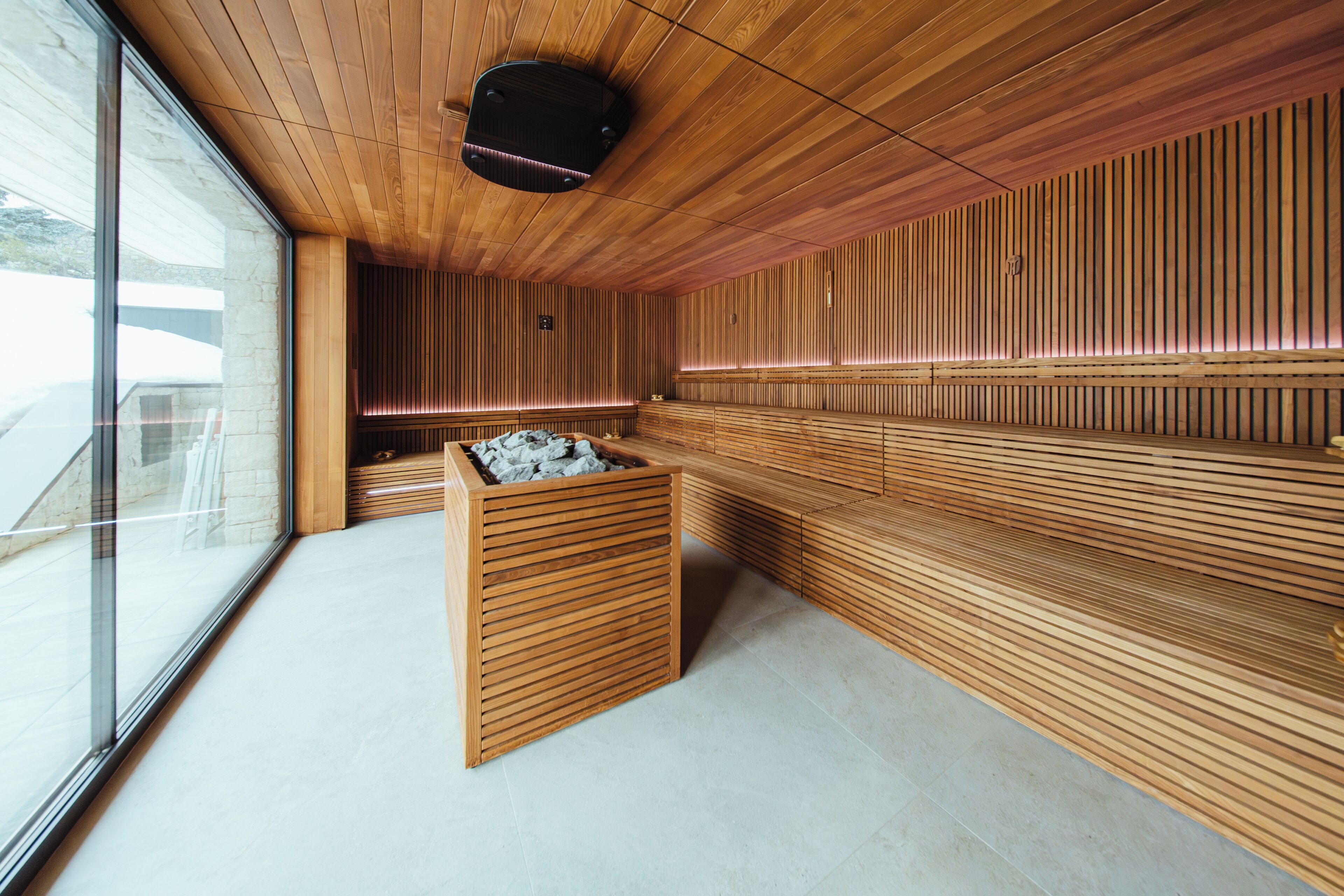 Un sauna moderne avec des bancs en bois et un bassin en pierre.